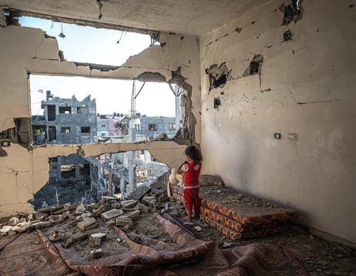 Palestinian girl stands in her destroyed home in Gaza
