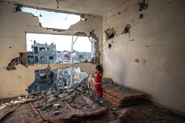 Palestinian girl stands in her destroyed home in Gaza