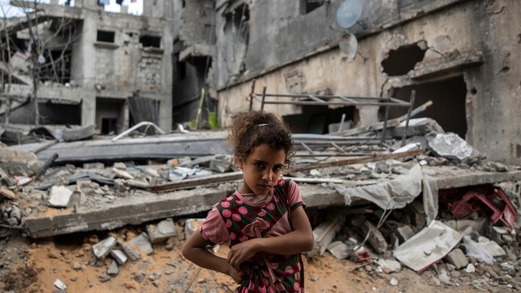A palestina Rahaf Nuseir, 10 anos, observa enquanto ela fica em frente às casas destruídas de sua família