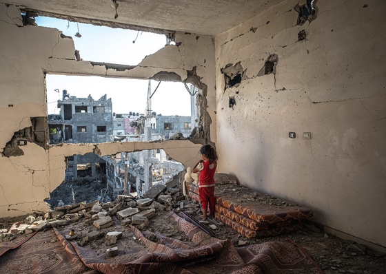 Palestinian girl stands in her destroyed home in Gaza